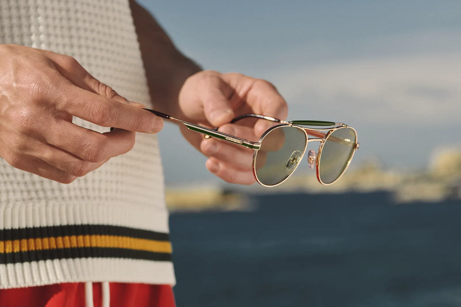 Gafas Carrera redondas metálicas doradas sobre fondo náutico